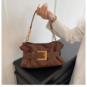 Close-up of brown pleated handbag with a large gold square buckle and chain strap