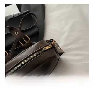 Detail of smooth gold zipper and leather texture on a dark brown underarm bag
