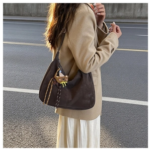 Detailed shot of coffee brown suede hobo bag featuring a cute brown bear charm accessory
