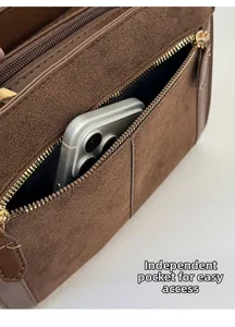 Detail view of the functional back zipper pocket on a brown suede tote bag