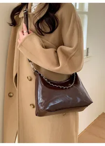 Detail of dark brown glossy patent leather shoulder bag with chic silver metal chain