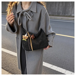 Detail of black suede hobo bag with cute charms worn with a grey wool coat in street style