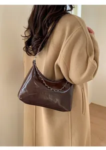 Detail of dark brown faux leather tote bag with silver chain and FASHION lettering