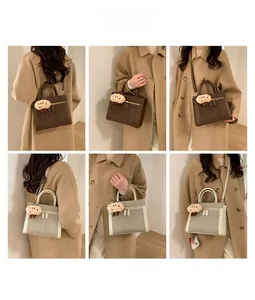Detail view of suede tote bags in coffee and beige with plush doll charm decoration