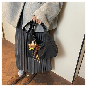 Detail of black retro hobo bag with cute bear and star charms on grey wool coat