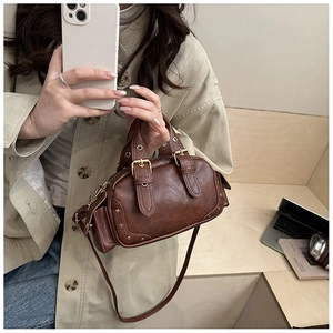 Close-up of vintage dark brown Boston bag with metallic rivets and side strap details