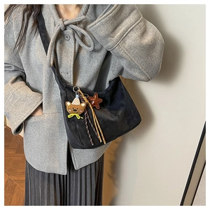 Detail of black crescent crossbody bag featuring cute bear plush and star charms