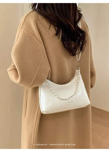 Detail of white glossy tote bag with silver chain and FASHION & BAGS text on camel coat