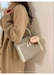 Close-up of minimalist retro tote bag with dual zipper detail and plush charm on model