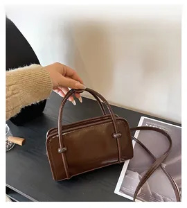 Detail of a brown vintage PU leather square handbag with a decorative round metal button
