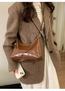 Detail of glossy brown leather tote bag with silver chain and BAGS lettering