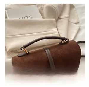 Details der braunen Wildledertasche mit glattem Ledergriff und goldenen Metallbeschlägen