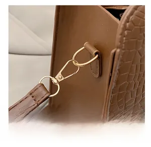 Detail of premium gold-tone metal hook on brown crocodile embossed leather shoulder bag