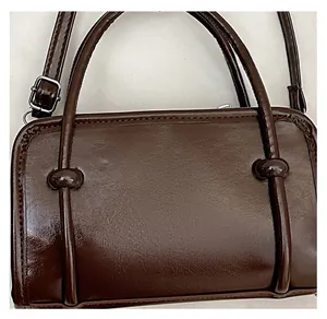 Detail of dark brown leather handbag showing fine texture and dual handles with metal rings