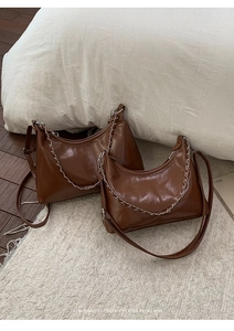 Detail view of two dark brown hobo bags in vintage oil wax leather with silver chains
