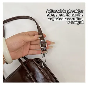 Detail of adjustable shoulder strap on dark brown leather handbag with silver metal buckle