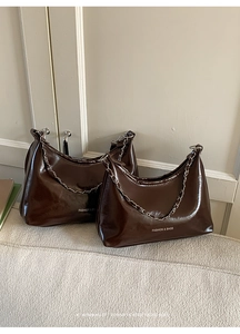 Detailed view of two dark brown shiny oil wax leather shoulder bags with silver chains