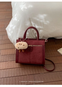 Detail of burgundy faux suede tote bag with metal zipper and plush charm accessory