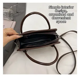 Detailed interior of the dark brown leather handbag showing minimalist space and lining