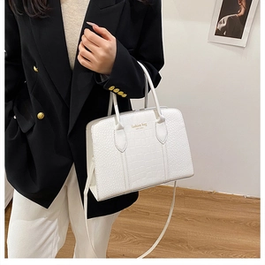 Detail of white crocodile embossed tote bag with gold lettering and sturdy handles