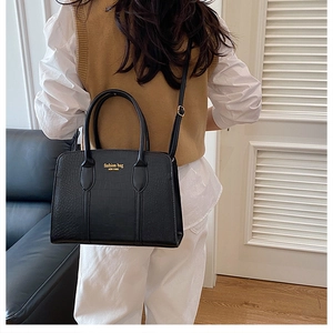 Detail of glossy crocodile-embossed tote bag with gold lettering shown in home setting