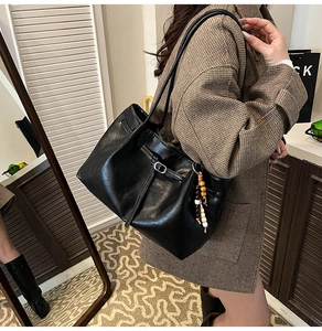 Detalle de bolso tote de cuero sintético negro con cuentas decorativas al hombro