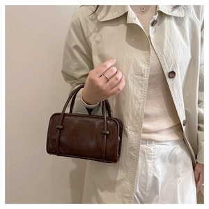 Detail of minimalist dark brown leather small square handbag with fine top handles