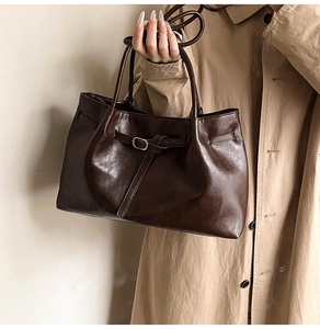 Primer plano de un bolso tote marrón oscuro con hebilla ajustable y textura de cuero