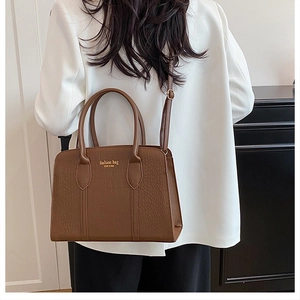 Detail of brown crocodile pattern tote bag with gold lettering shown on shoulder