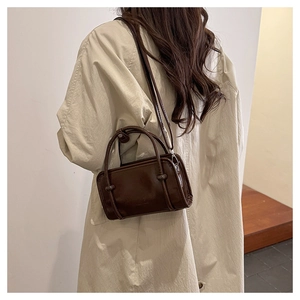 Side view of dark brown faux leather square handbag worn with a beige trench coat