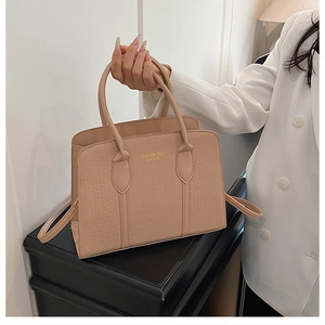 Detail of beige crocodile pattern handbag with New York lettering and gold hardware