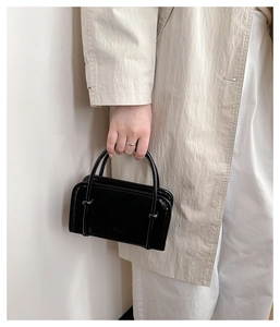 Close-up of black glossy leather handbag with fashion embossing and metal buckle