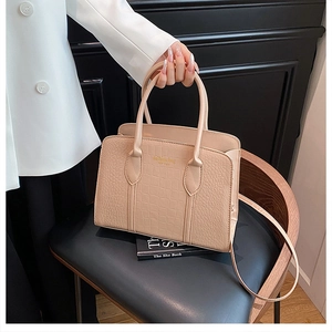 Detail of beige crocodile embossed tote bag featuring gold fashion bag lettering