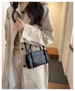 Fashionable black glossy patent leather small square bag styled with a beige trench coat