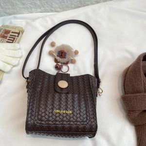 Brown woven bucket bag with fashion logo, teddy bear pendant and soft fabric background