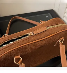 Detail of smooth gold zipper and premium brown suede texture on a vintage baguette bag