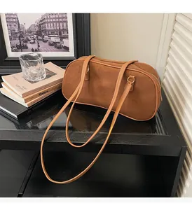 Detailed view of the brown suede bowling bag with golden zippers and double shoulder straps