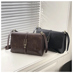 Detail of vintage faux leather crossbody bags in brown and black with metal buckle