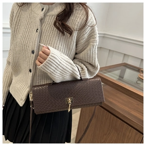 Detail of dark brown faux crocodile texture with gold metal buckle on a woven bag