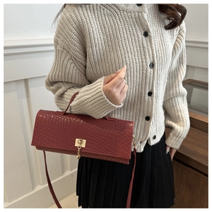 Detalle del bolso rojo trenzado con cierre giratorio de metal dorado en conjunto de modelo