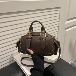Vintage brown leather Boston bag with gold rivets and adjustable strap in lifestyle setting