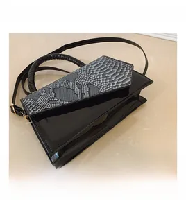 Detail of black faux snake skin and patent leather square handbag with top handle