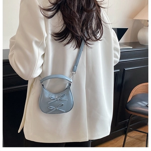 Back view of a mini light blue bow shoulder bag styled on a white blazer for women
