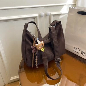 Brown vintage faux leather tote bag with adjustable strap and bear charm on a table