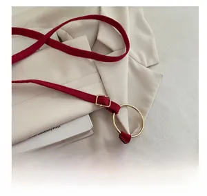 Détail d'un sac bandoulière bordeaux en daim avec anneaux dorés et boucle de réglage chic