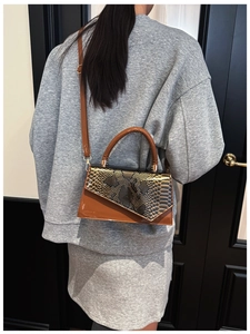 Detail of retro patchwork handbag with snake skin texture and polished brown leather