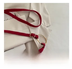Vue détaillée du sac bandoulière en daim rouge foncé avec rivets dorés et boucle