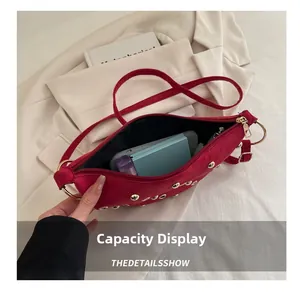 Capacité intérieure du sac d'épaule en daim rouge avec rivets dorés et fermeture éclair