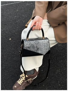 Detailed close-up of a snake-print crossbody bag with premium black leather trim and hardware