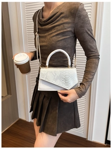 Detail of white square bag with snake skin texture and geometric flap design